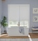 A blue purple romantic bathroom with soaking tub in front of large window with white blackout cordless roller shades