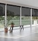 A rustic bench and plants in front of large windows with black 10 percent cordless eco-efficient solar screen shades