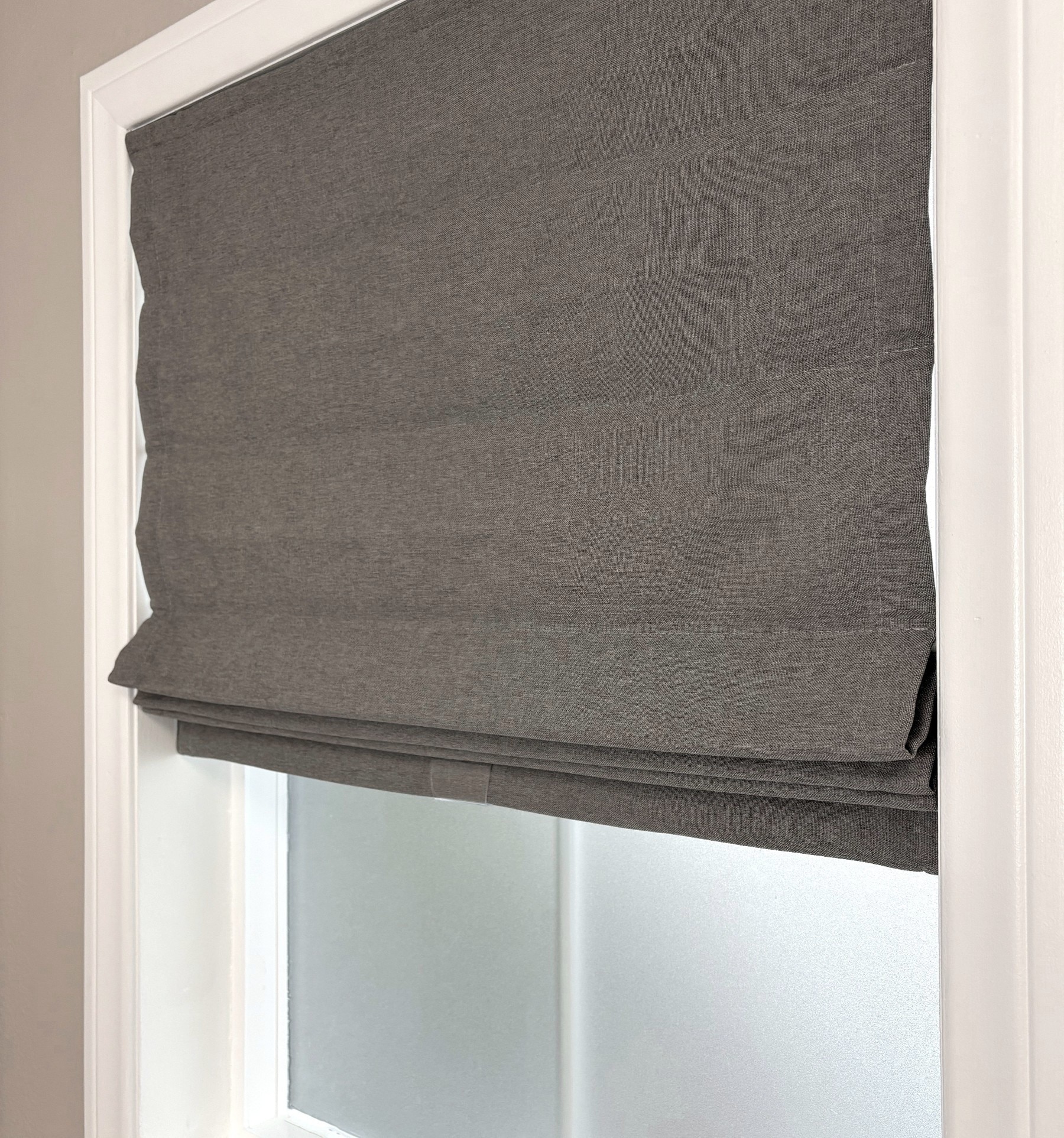 Blindsgalore Essential Roman Shade shown in flat fold with cordless lift. Shown in Newport Smoke.